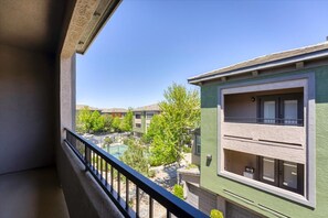 Un balcón con vistas a una zona residencial, que incluye edificios de varios pisos y una cancha de tenis.