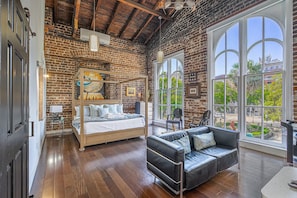 Relax in this stylish room with a large bed, black sofa, and floor-to-ceiling windows offering views of the outdoors.