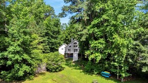 A house surrounded by dense trees, a grassy yard, and a small dock. - Tide & Timber | Community Swiming Pool | Pet-Friendly (Fee) (Littleton)
