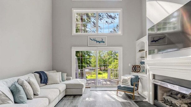 A modern living room with a sofa, fireplace, and large windows. - Tide & Timber | Community Swiming Pool | Pet-Friendly (Fee) (Littleton)
