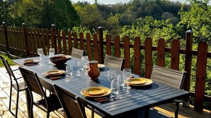 A deck with a table set for dining, surrounded by a wooden fence, overlooking a lush landscape. - Gîte Le Belvédère du Lac between lakes and castles of the Dukes of Burgundy (Civry-en-Montagne)