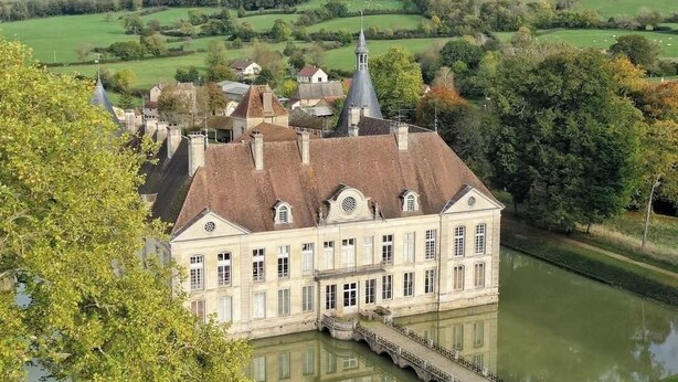 A large, historic building with a central tower, surrounded by a calm river and lush greenery. - Gîte Le Belvédère du Lac between lakes and castles of the Dukes of Burgundy (Civry-en-Montagne)