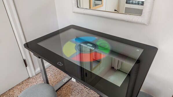 Une table avec un plateau en verre et un design circulaire, une prise électrique et un thermostat mural.