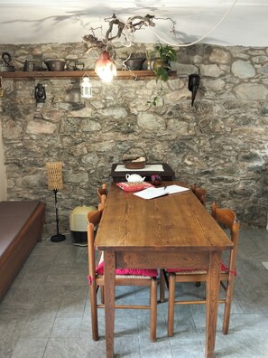 A wooden dining table with chairs, a stone wall, a hanging light fixture, and a floor lamp. - The mountain Cabin (scopa)
