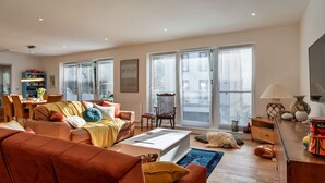 A spacious living room with a large sofa, a coffee table, and a dining area with a table and chairs.