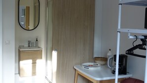 A modern bathroom with a wooden vanity, a mirror, and a towel rack. - Superbe Studio Neuf au Cœur des Carmes - Elegance & Comfort (Toulouse)