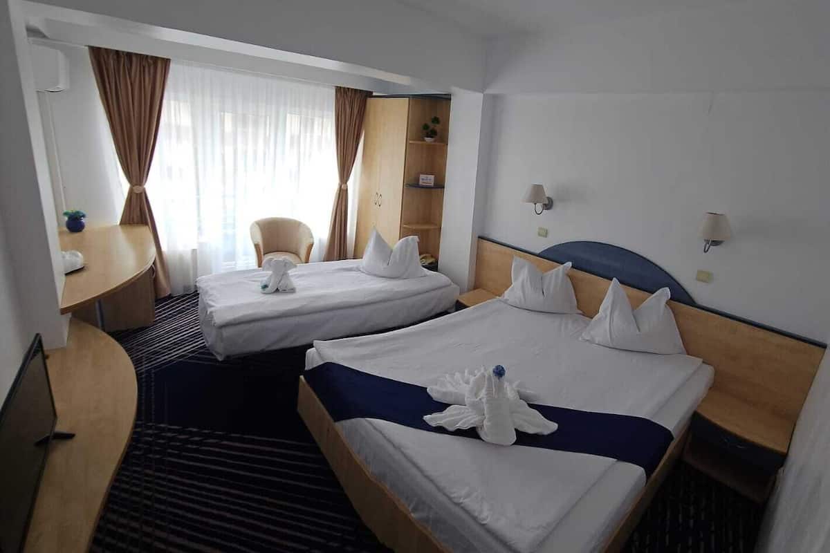 Ein Hotelzimmer mit zwei Betten, einem Schreibtisch, einem Stuhl und einem Kleiderschrank.