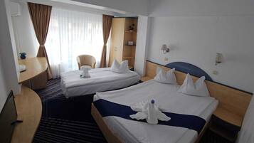 A hotel room with two beds, a desk, a chair, and a wardrobe.