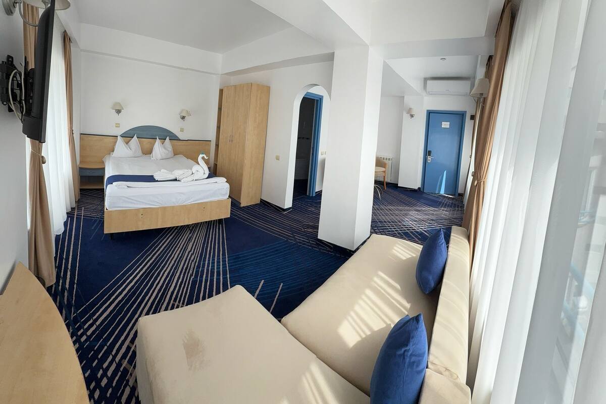 Ein Hotelzimmer mit Bett, einer Couch, einem Kleiderschrank und einem Schreibtisch.