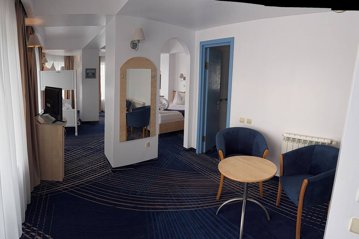 Ein Hotelzimmer mit Bett, Schreibtisch, Computer, Stuhl und einem kleinen Tisch.