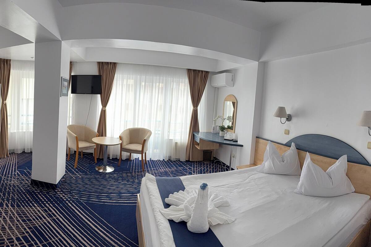 Ein Hotelzimmer mit einem Etagenbett, einem Schreibtisch mit Stuhl, einem runden Tisch und einem Bett mit einem Zierkissen.