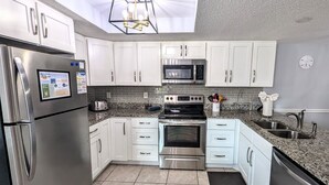 A modern kitchen with stainless steel appliances, white cabinets, a microwave, and a built-in oven. - Coastal Charm at Sea Club #13-Pool View and Fishing Dock (Indian Shores)