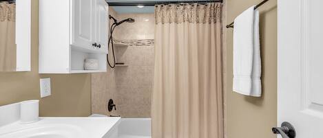 Un baño con bañera, inodoro y cortina de ducha.