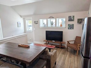 A modern living room with a TV, wooden furniture, and artwork on the walls.