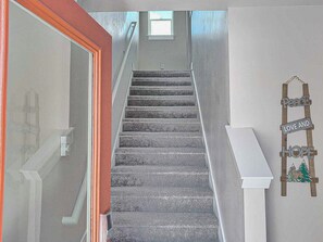 A staircase with a wooden handrail and a wall-mounted sign that reads "Peace Love and Hope."