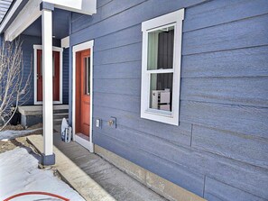 A two-story house with a blue exterior, red front door, and a window with a white frame.