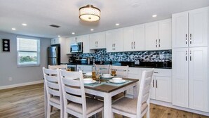 A modern kitchen with white cabinets, a dining table with chairs, and a black countertop.