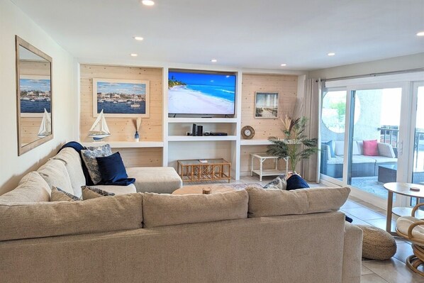 Relax in this inviting living space with a large flat-screen TV, comfortable sofa, and a beautiful view through the sliding glass door.