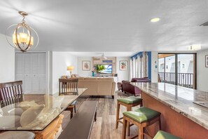 A spacious living area with a dining table, sofas, and a TV. - Coral Reef Retreat, SeaClub #44~Pool, Fishing (Indian Shores)