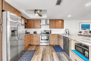 A modern kitchen with stainless steel appliances, wooden cabinets, and a herringbone tile backsplash.