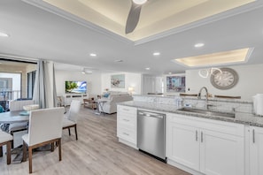 Una cocina moderna con armarios blancos, lavavajillas de acero inoxidable y una isla grande con pileta integrada.