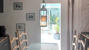 A dining area with a glass table and wooden chairs, a hanging lantern, and a view of the outdoors.