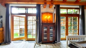 A cozy room with large windows, a fireplace, and a wooden bench.