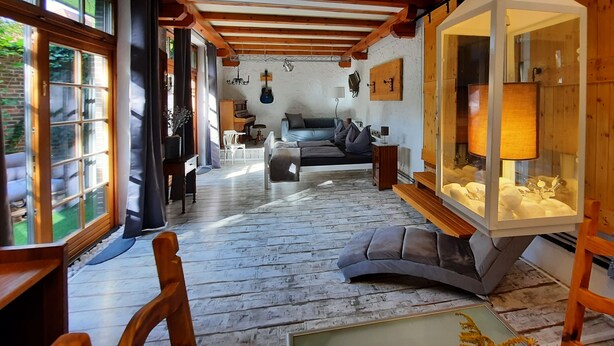 A cozy living room with a sofa, a glass cabinet with decorative items, and a piano.
