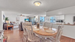Amplia sala de estar con una mesa de comedor, sillas y una cocina al fondo.