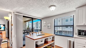 Una cocina moderna con encimera de madera, armarios blancos y vistas a la ciudad a través de amplios ventanales.