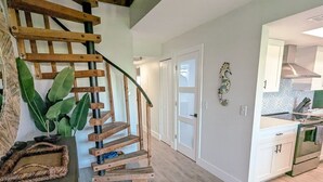 A modern kitchen with white cabinets, a built-in oven, and a wooden staircase.