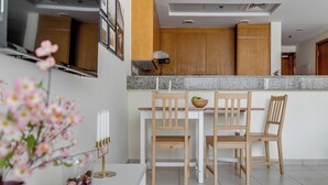 Une cuisine moderne avec des meubles en bois, un plan de travail en granit et un coin repas comprenant quatre chaises en bois et une table blanche.