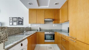 Une cuisine compacte avec des meubles de rangement en bois, un four encastré et un lave-linge.