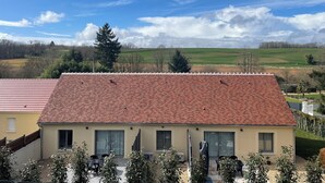 A two-story building with a red-tiled roof, large windows, and a flat roof terrace with outdoor seating. - Welcome to Gîtes "Le Duo De Galerne"! 5 minutes from ZooParc de Beauval (Seigy)