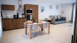 A modern kitchen with wooden cabinets, stainless steel appliances, and a dining area with a table and chairs. - Welcome to Gîtes "Le Duo De Galerne"! 5 minutes from ZooParc de Beauval (Seigy)