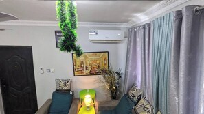 Relax in this stylish living room with a sofa, floor lamp, and potted plant, offering a view of the city.