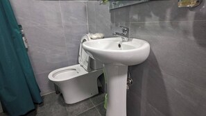 Bathroom features a toilet, sink, and tiled walls.