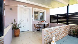 Eine überdachte Terrasse mit Tisch, Stühlen, einer Topfpflanze und einer weißen Schwan-Dekoration.
