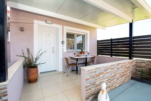 Un patio techado con mesa y sillas, una planta en maceta y una decoración de cisne blanco.