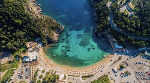 Vista aérea de una zona costera con playa, estacionamientos y edificios.