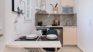 Una cocina moderna con comedor para dos, que incluye una encimera de mármol, estufa integrada y microondas.