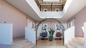 Ein mehrgeschossiges Interieur mit einer zentralen Treppe, einem Oberlicht und zwei Hängestühlen.