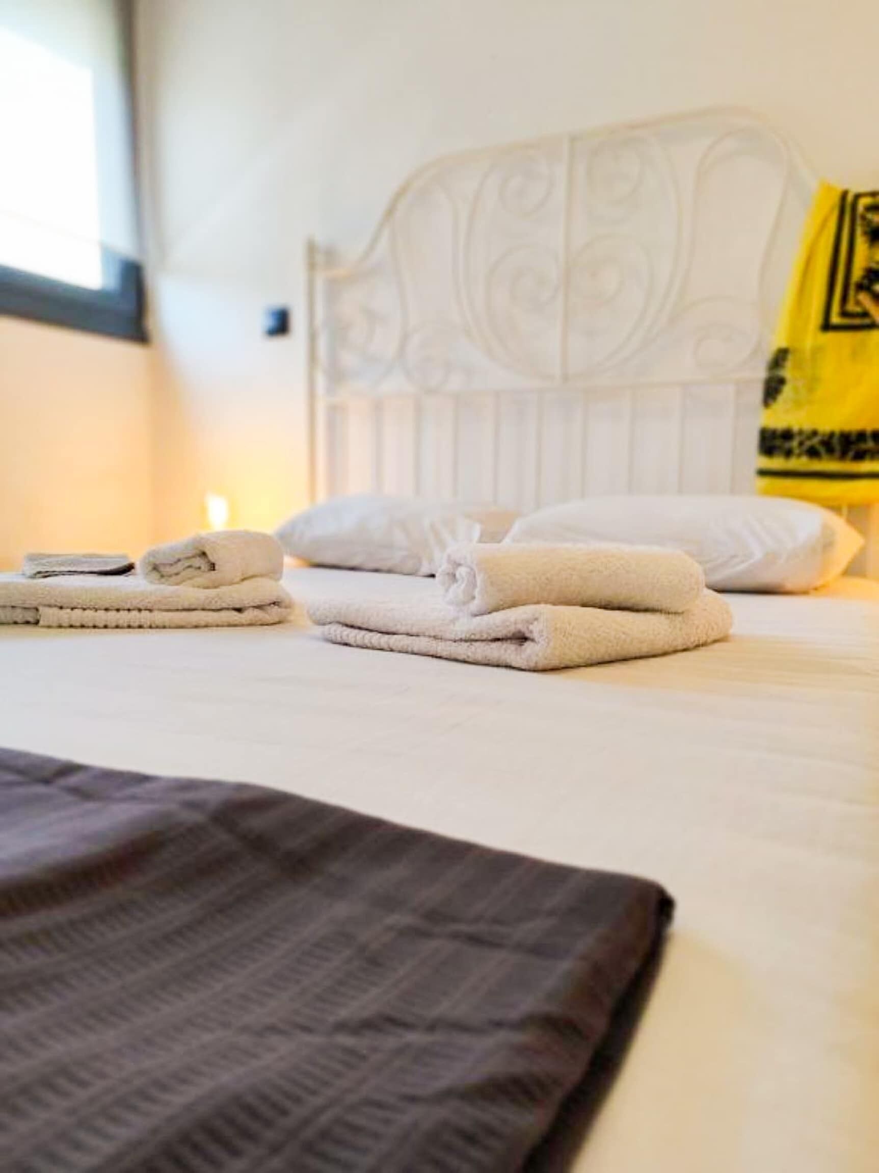 A neatly made bed with folded towels and a brown blanket.