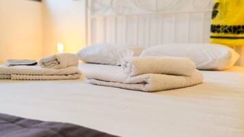 A neatly made bed with folded towels and a brown blanket.
