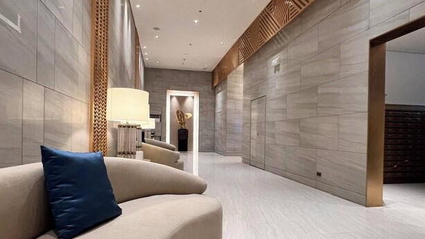 Un vestíbulo moderno con un sofá curvo, una lámpara y un panel decorativo de pared.