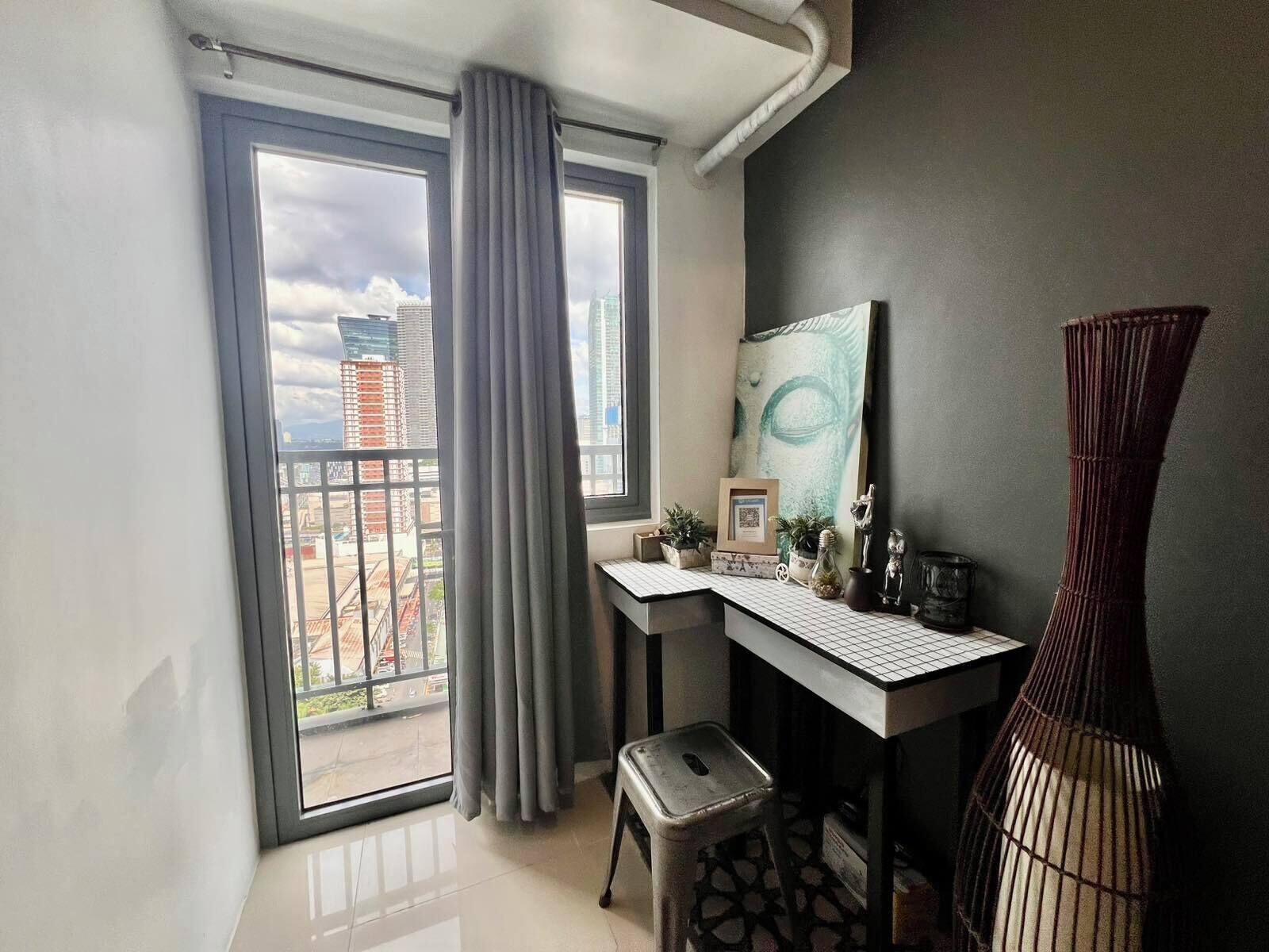 A modern apartment with a balcony, a desk with a computer, and a large window with curtains.