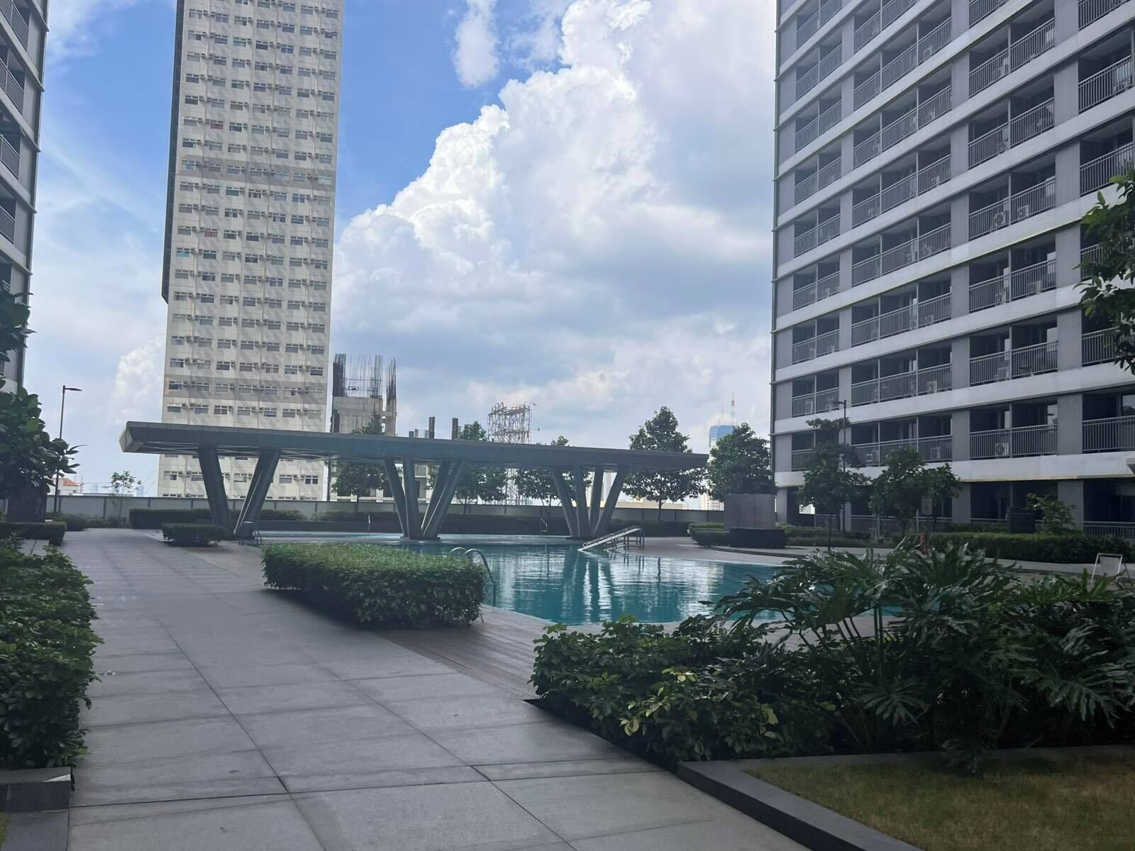 A modern residential area with high-rise buildings, a swimming pool, and a pedestrian bridge.