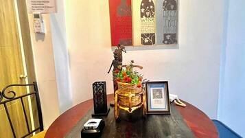 A round table with a framed certificate, a small black object, a decorative basket with flowers, and a QR code.