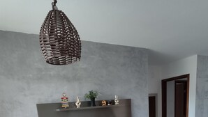 Een moderne woonkamer met een flatscreen televisie, een geweven lamp, een zwarte ventilator en een bruine bank.