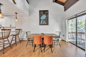 A dining area with a wooden table, four chairs, and a large window with a view of a deck. - Alpine Retreat In The Heart Of Incline Village 2 Bedroom Condo (Incline Village)